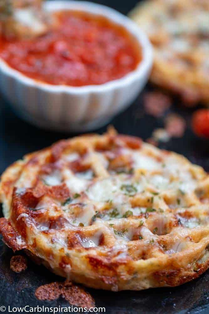 two small pizzas on a black surface next to some tomatoes and other condiments