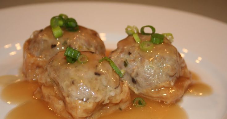 two meatballs covered in sauce on a white plate