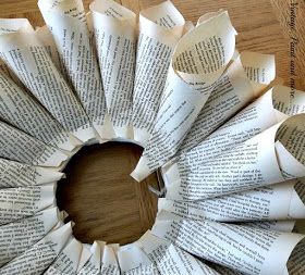 a wreath made out of book pages sitting on top of a wooden table