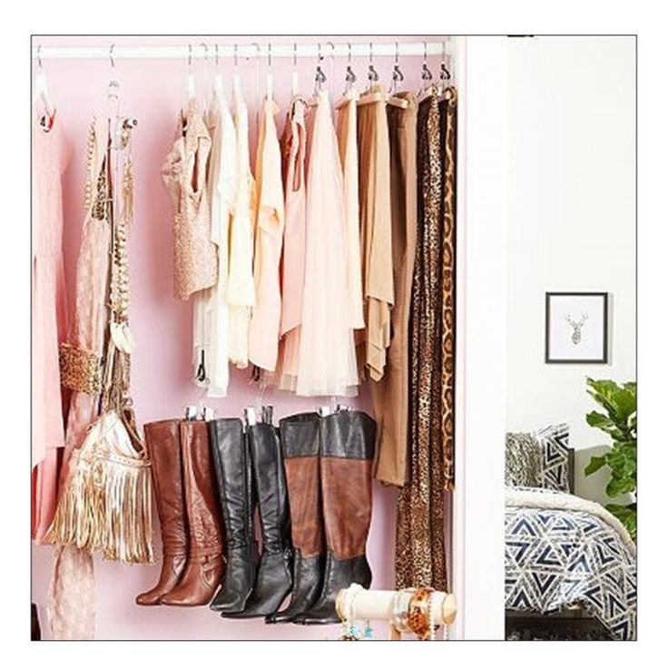 a closet filled with lots of different types of clothes and boots hanging from hooks on the wall