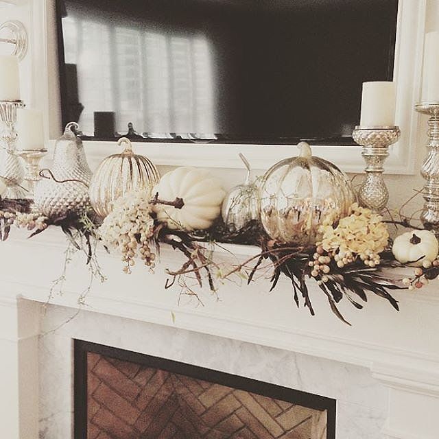 a fireplace mantel with candles and flowers on it, in front of a tv