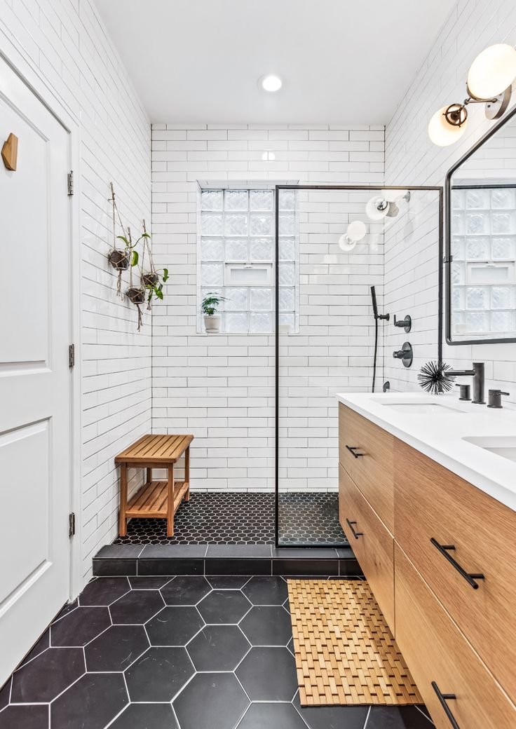 a bathroom with black and white tile flooring, wooden cabinets and a walk in shower