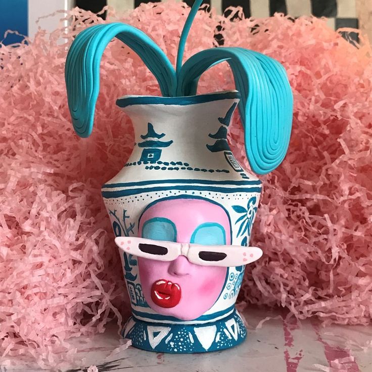 a ceramic vase with a pink and blue flower in the shape of a clown's head