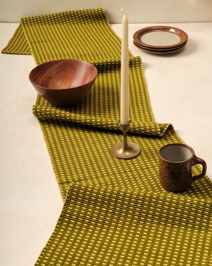 a table topped with plates and cups on top of a white table cloth next to a candle