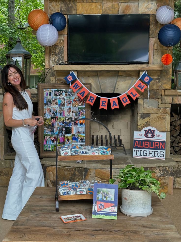 a woman standing in front of a table with pictures on it and decorations around her