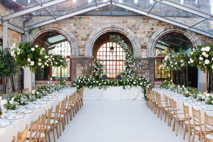 an indoor venue with tables and chairs set up for a formal dinner or wedding reception