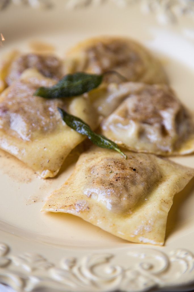 three ravioli with spinach and cheese on a white plate