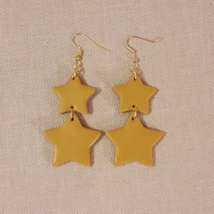 three yellow stars are hanging from gold earrings