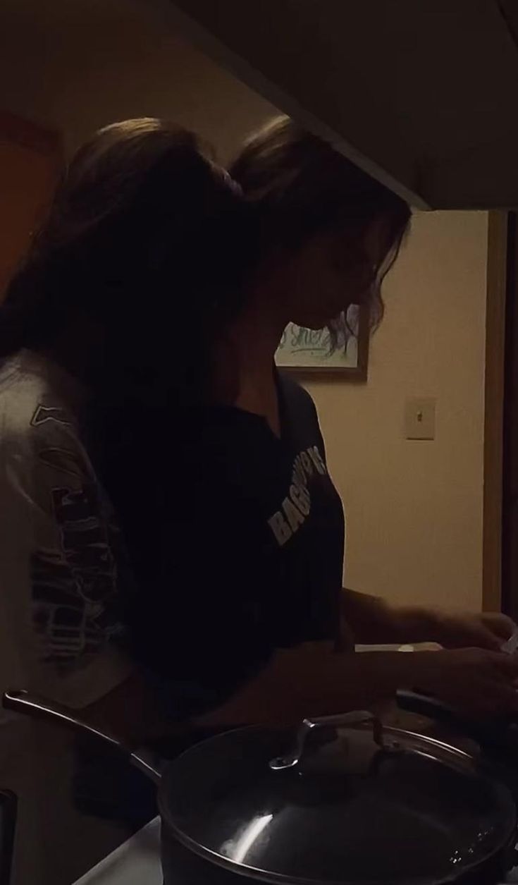 a woman standing in front of a stove with a pan on it