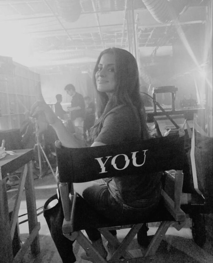 a woman sitting in a wooden chair with the word you on it's back