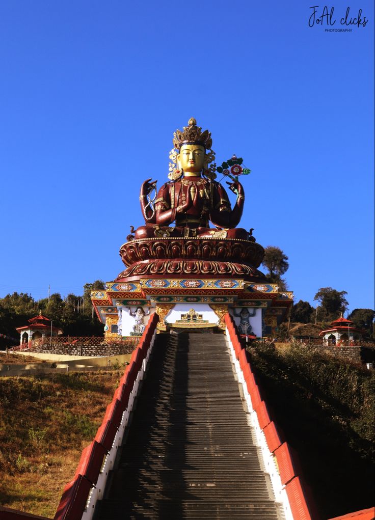 the stairs lead up to an elaborately decorated statue on top of a hill in front of a blue sky