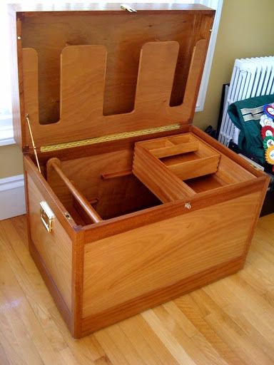 an open wooden chest sitting on top of a hard wood floor