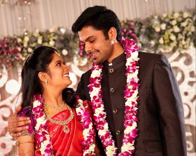 a man and woman standing next to each other in front of a flower leis