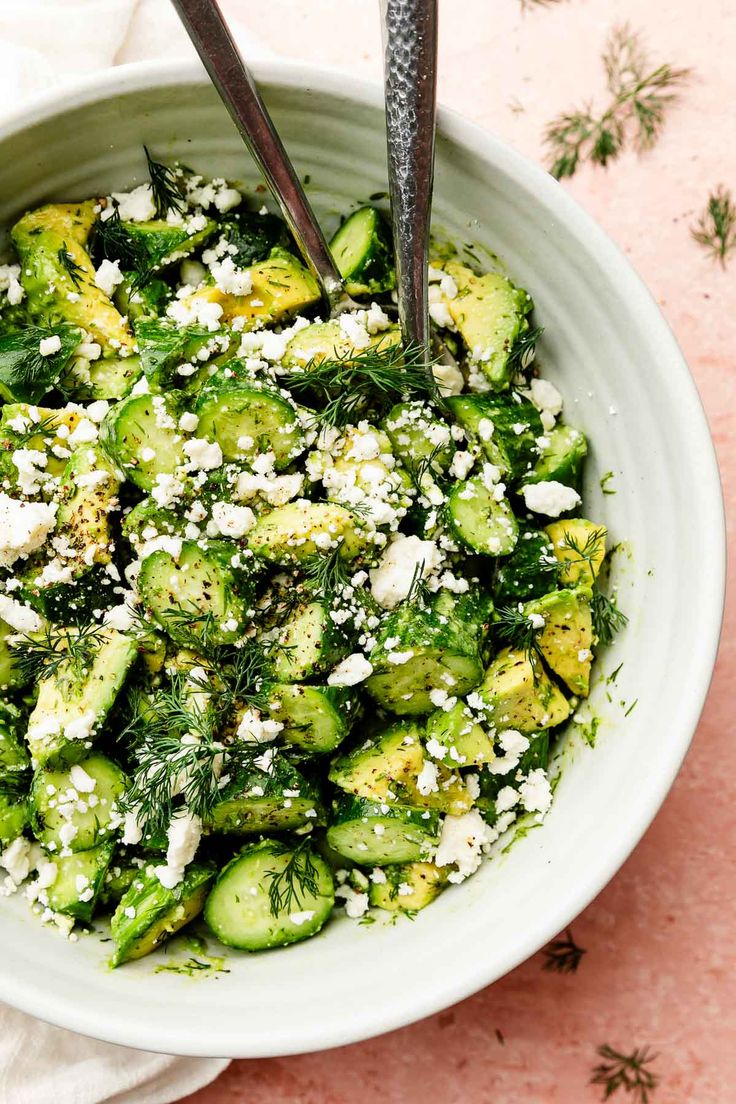 a white bowl filled with cucumber and feta cheese on top of a table