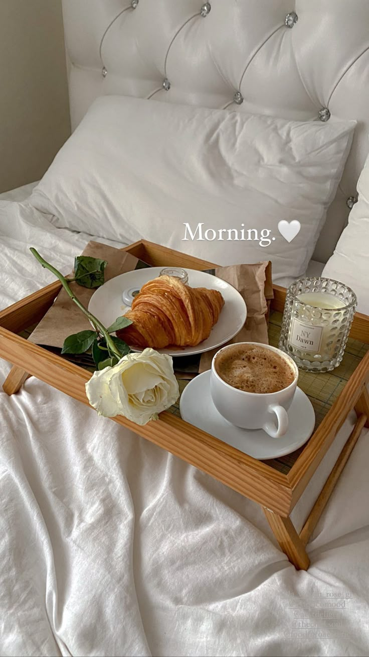 a tray with coffee and croissants on it sitting on top of a bed