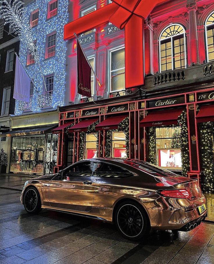 a car parked in front of a building with christmas lights on it's windows