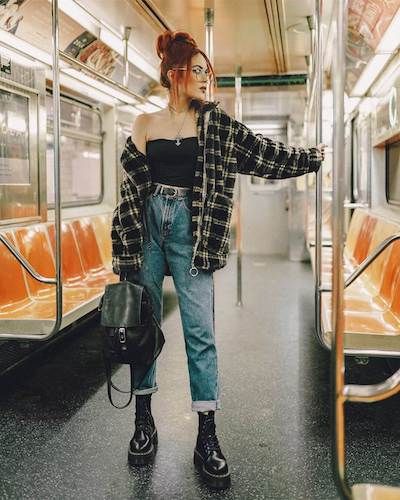 a woman standing on a subway train with her hand in her pocket and looking off to the side