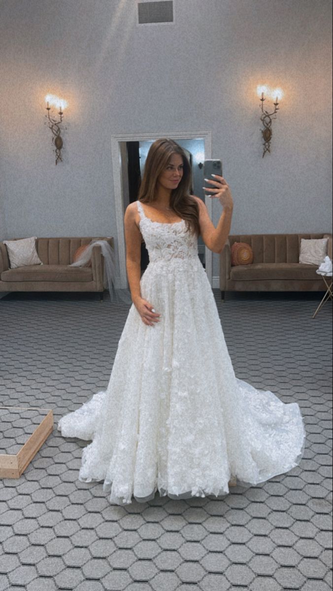 a woman in a white dress taking a selfie with her cell phone while standing on the floor