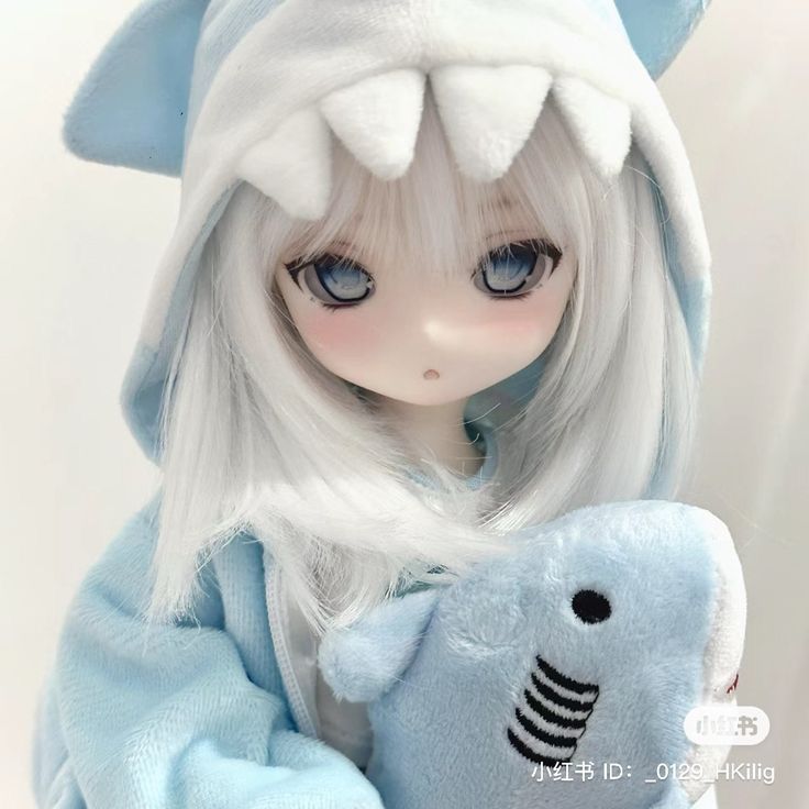 a doll with white hair and blue eyes holding a stuffed animal