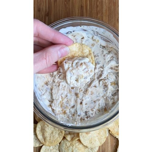 a person dipping crackers into a bowl of dip