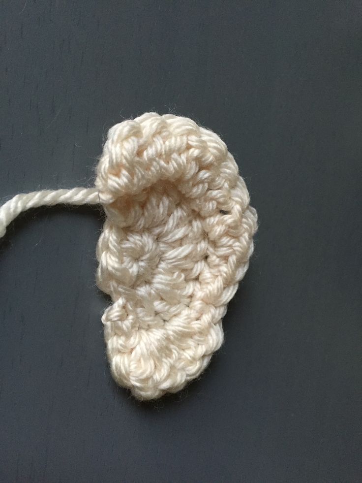 a white crocheted object is laying on a black surface and it appears to have been made out of yarn