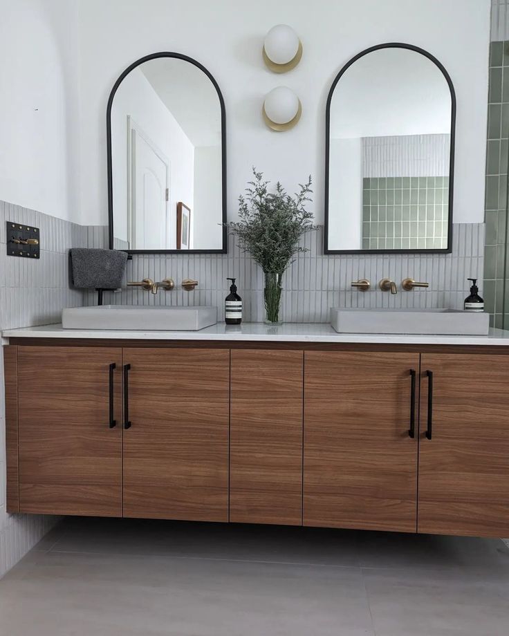 a bathroom with two sinks and mirrors on the wall