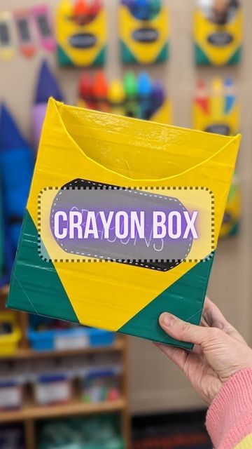 a person holding up a box with the word crayon box on it in front of them