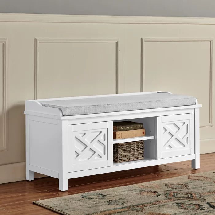 a white bench sitting on top of a hard wood floor next to a rug and wall