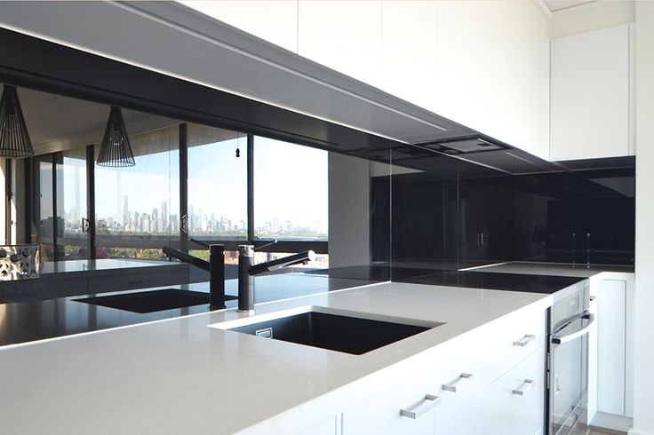 an empty kitchen with white cabinets and black counter tops in front of a large window