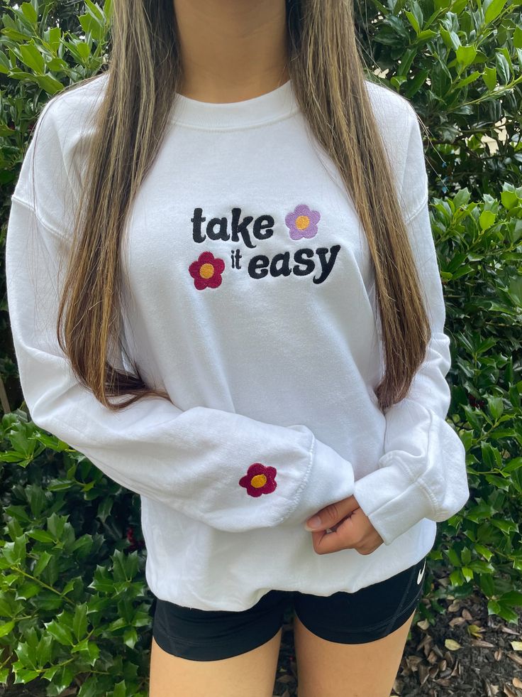 Take It Easy with this adorable crewneck sweatshirt! It has beautiful flower detailing and a flower on the sleeve. This is the perfect addition to anyone's wardrobe. The Unisex Sizing makes the sweatshirt run slightly larger than your average sweatshirt for women. Most men find their normal size to be more snug. If you want a slightly looser fit, size up one size. Please check out our size chart for measurements to ensure an accurate fit. PLEASE BE SURE TO INPUT YOUR CORRECT SIZE/COLOR + SHIPPIN Iron On Sweatpants Ideas, Cute Long Sleeve Sweatshirt For Everyday, Trendy Crew Neck Sweatshirt For Spring, Trendy Crew Sweatshirt For Spring, Casual Long Sleeve T-shirt With Floral Embroidery, Trendy Spring Crew Neck Tops, Trendy Crew Neck Top For Spring, Basic Spring Sweatshirt For Everyday, Basic Spring Sweatshirt