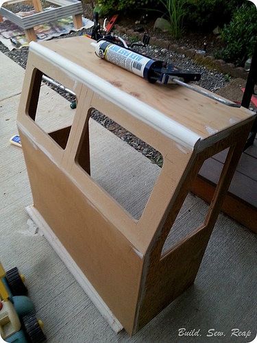 an unfinished wooden table with paint and tools on it, sitting in the middle of a yard