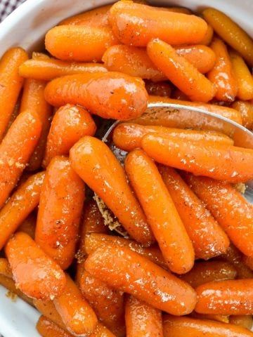 a bowl filled with baby carrots covered in powdered sugar on top of a checkered table cloth