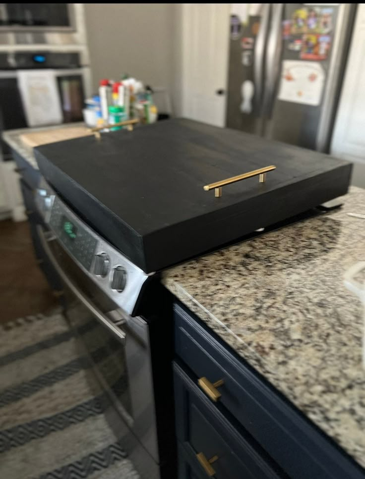 a black box sitting on top of a counter next to a stove and oven in a kitchen