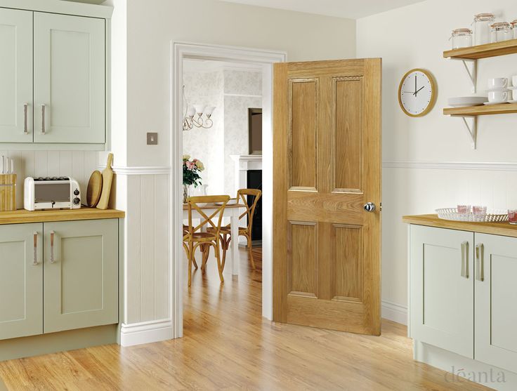 an open door leading to a kitchen with wooden floors and white walls, in front of a breakfast nook