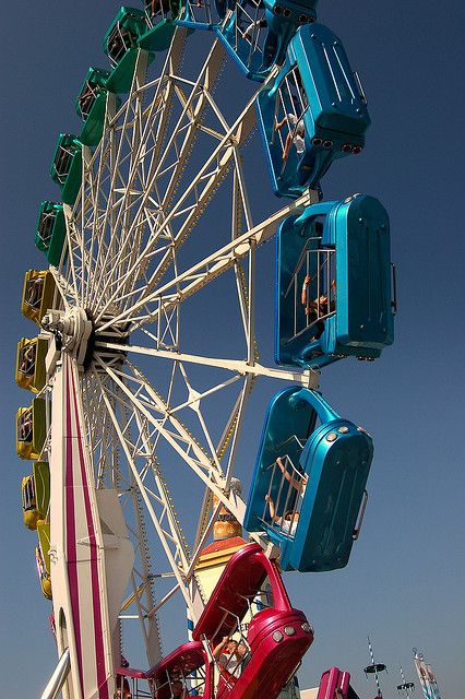 the ferris wheel is brightly colored and has several seats