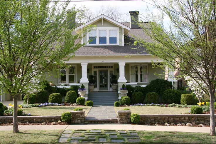 a large white house with lots of trees and bushes around it's front entrance