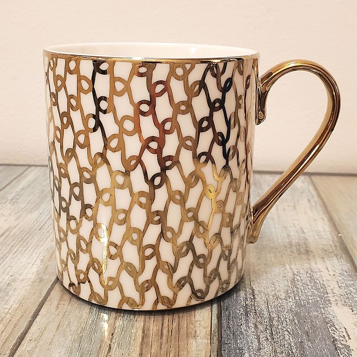 a white and gold coffee cup sitting on top of a wooden table