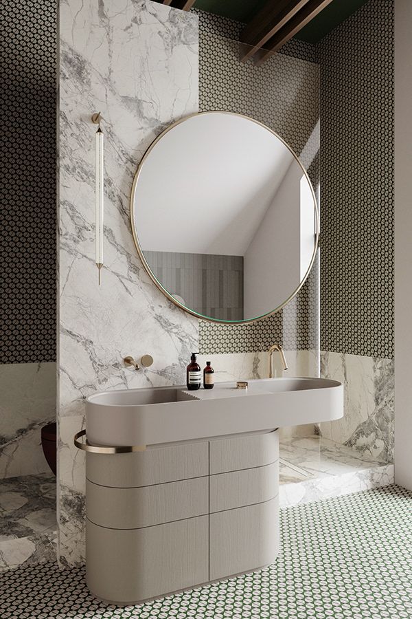 a bathroom with marble walls and flooring has a round mirror on the wall above the sink