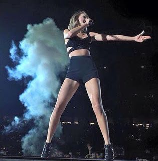 a woman standing on top of a stage with her arms out in front of the crowd