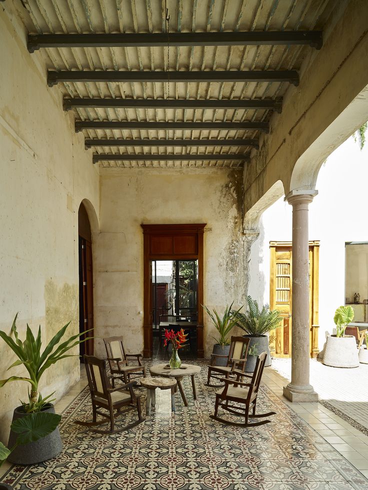 an outdoor patio with rocking chairs and potted plants