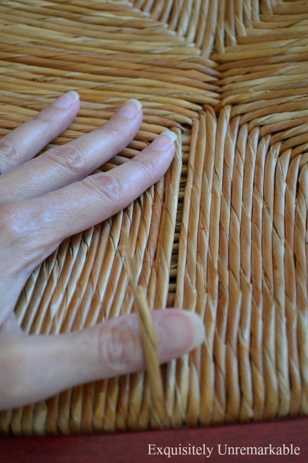 a person's hand on top of a woven wicker table cloth with nails sticking out of it