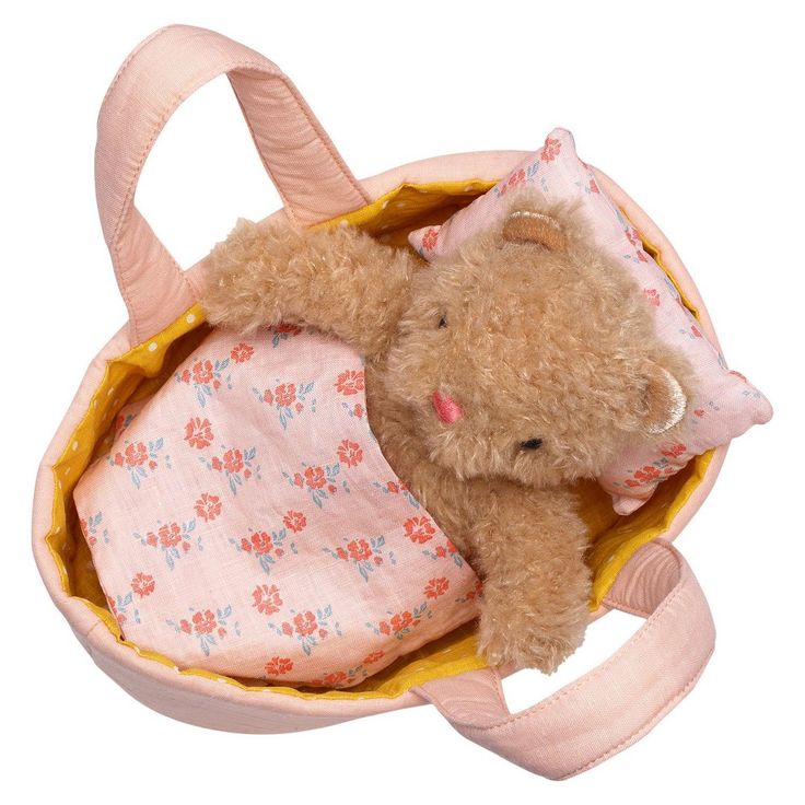 a teddy bear in a pink bag with flowers on the bottom and sides, laying down