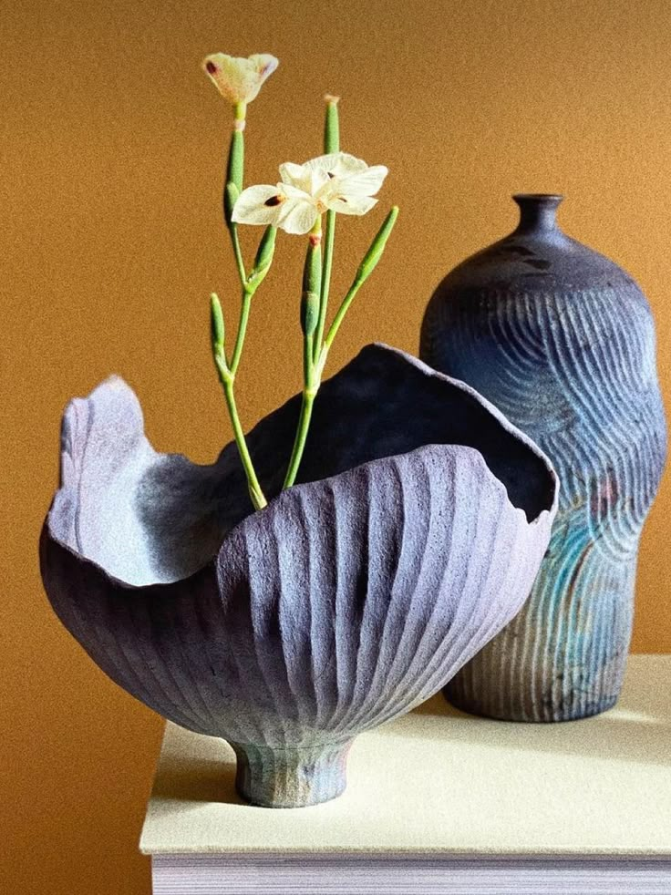 two vases sitting on top of a table with flowers in them next to each other