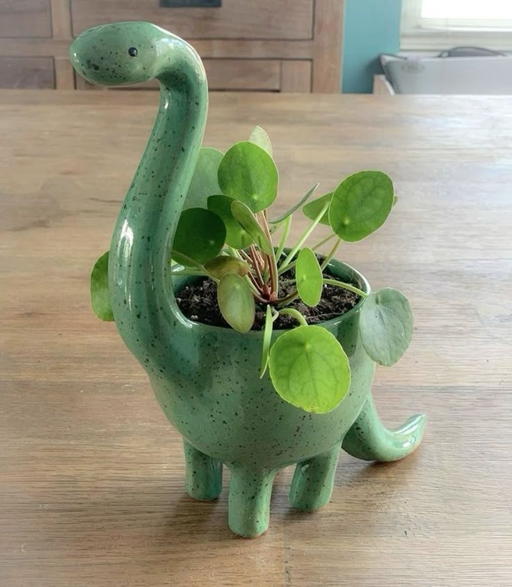 a green dinosaur planter sitting on top of a wooden table