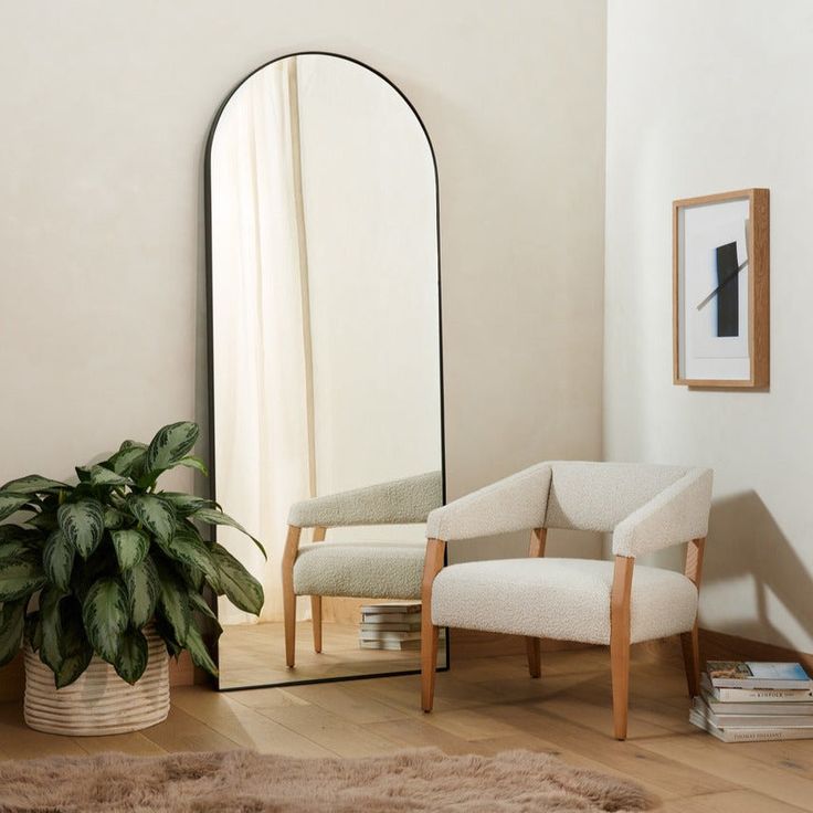 a mirror sitting on top of a wooden floor next to a chair and potted plant