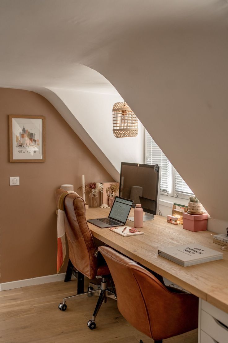 a desk with a laptop computer on top of it next to a chair and window