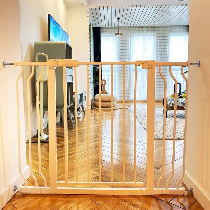 a living room with hard wood floors and a white iron gate that is open to let in light