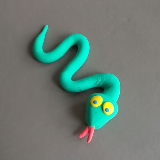 a green toy snake with yellow eyes on a gray surface