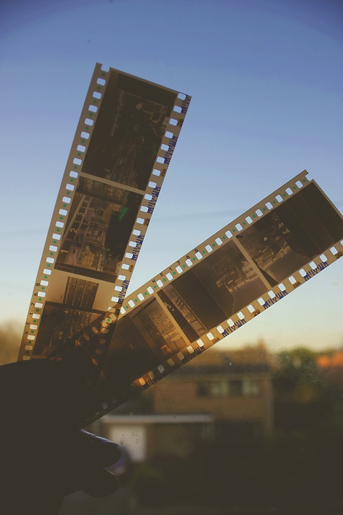 the film strip is being held up by someone's hand in front of a building