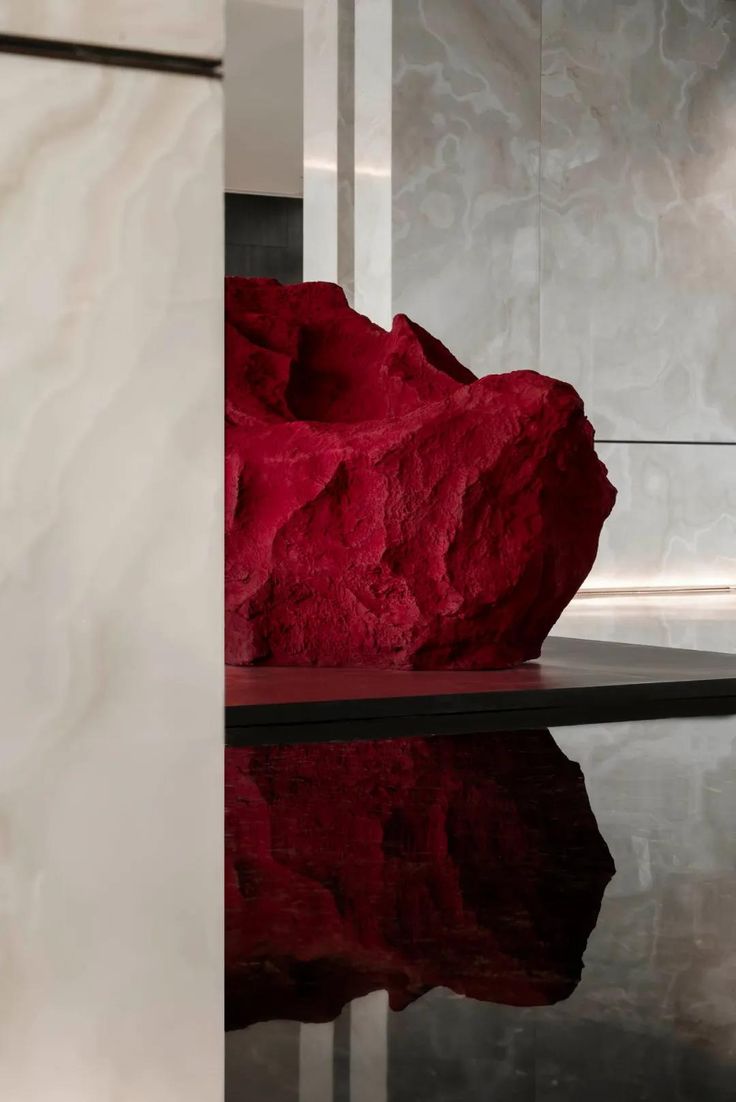 a red rock sitting on top of a black table next to a white wall and floor